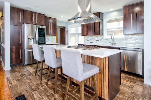 kitchen featuring appliances with stainless steel finishes, a center island, island exhaust hood, and a breakfast bar area