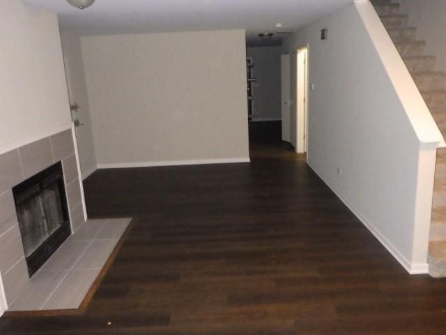 unfurnished living room with a tile fireplace and dark hardwood / wood-style flooring