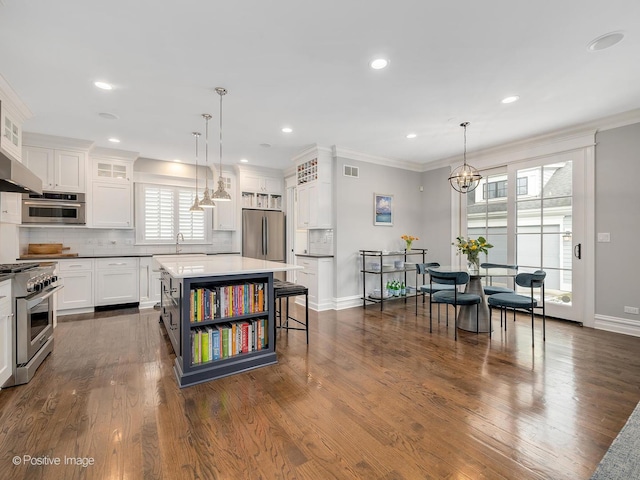 kitchen featuring stainless steel appliances, a center island, pendant lighting, and white cabinets