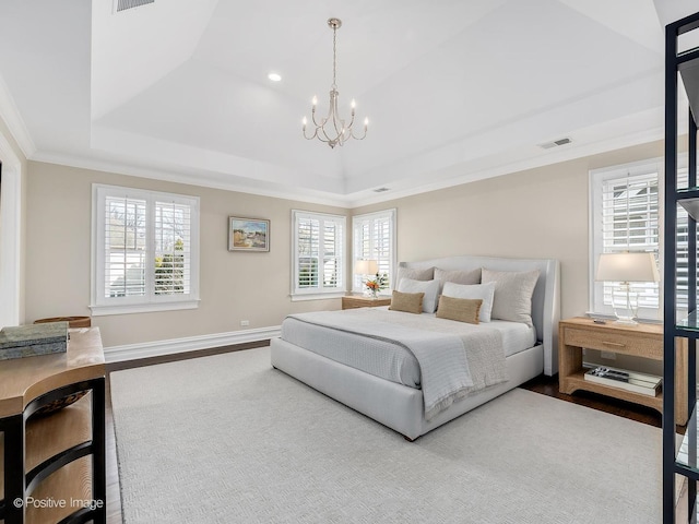 bedroom with ornamental molding, wood-type flooring, an inviting chandelier, and a tray ceiling