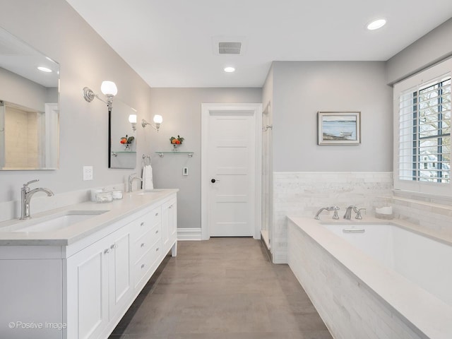 bathroom featuring vanity and tiled tub