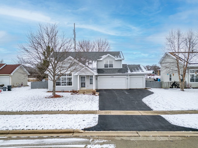 traditional home with driveway, roof with shingles, an attached garage, and fence