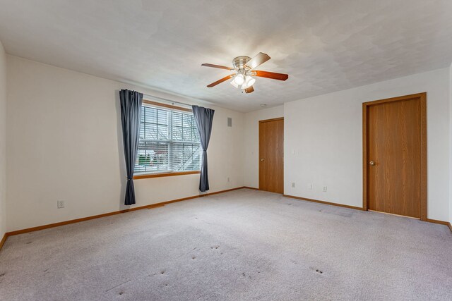 spare room with carpet floors, ceiling fan, and baseboards