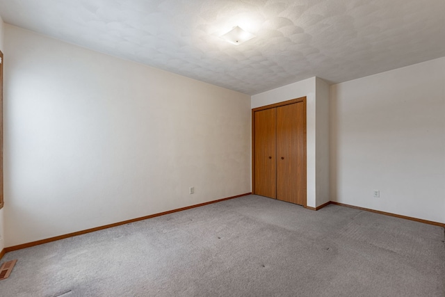 unfurnished bedroom featuring a closet, light colored carpet, and baseboards