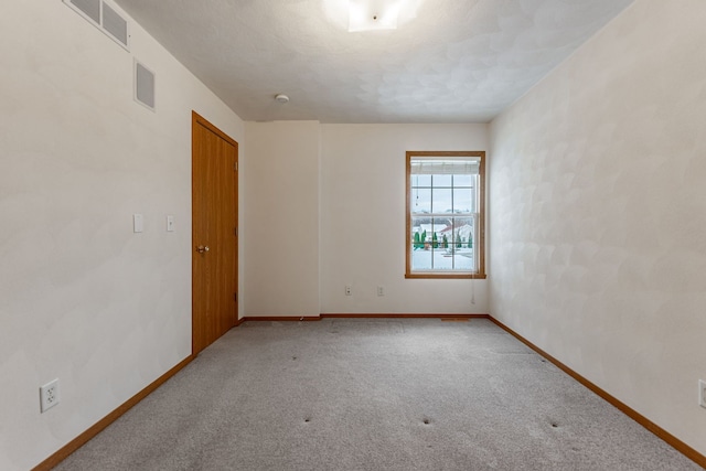 unfurnished room featuring baseboards, visible vents, and carpet flooring