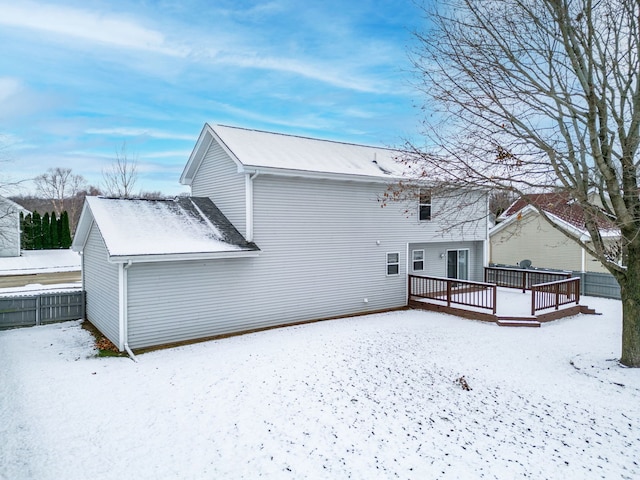 snow covered property featuring fence and a deck