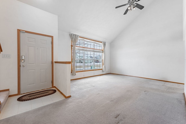 carpeted entryway featuring high vaulted ceiling, tile patterned flooring, baseboards, and a ceiling fan