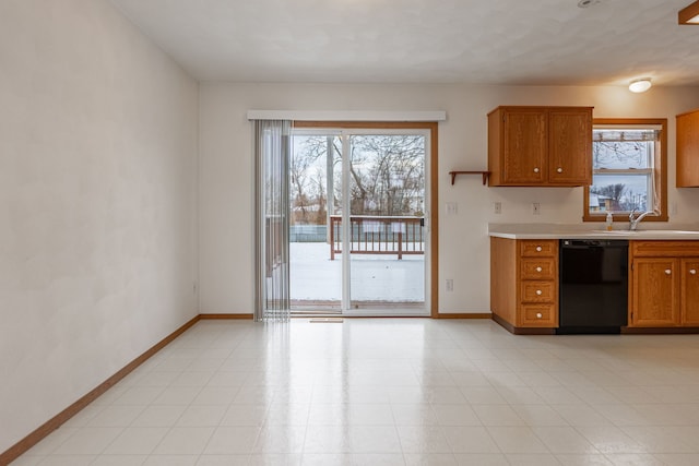 kitchen with brown cabinets, light countertops, a sink, dishwasher, and baseboards