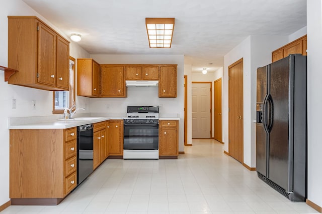 kitchen with brown cabinetry, under cabinet range hood, light countertops, black appliances, and a sink