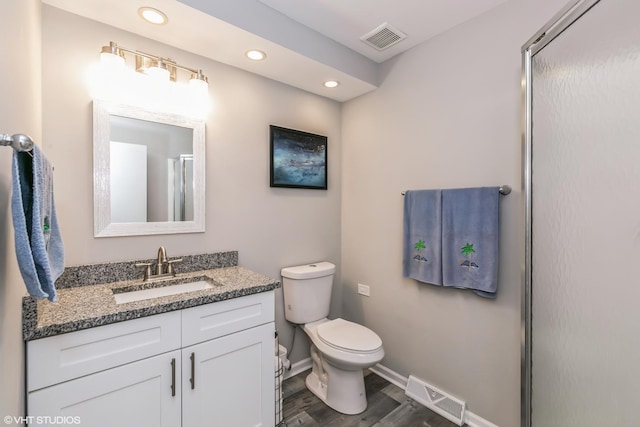 bathroom featuring a shower with door, vanity, wood-type flooring, and toilet