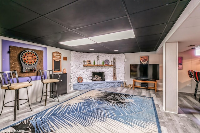 living room featuring a fireplace, hardwood / wood-style floors, and a paneled ceiling