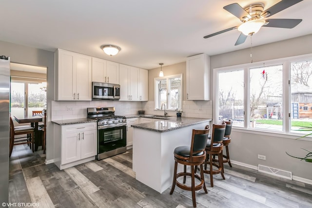 kitchen with white cabinetry, sink, kitchen peninsula, and stainless steel appliances