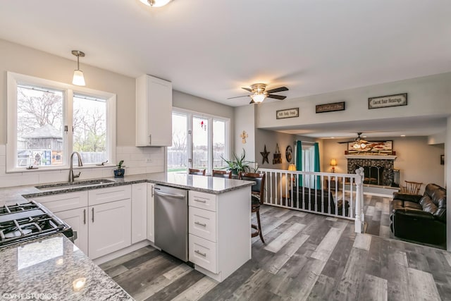 kitchen featuring light stone counters, stainless steel appliances, sink, white cabinetry, and hanging light fixtures