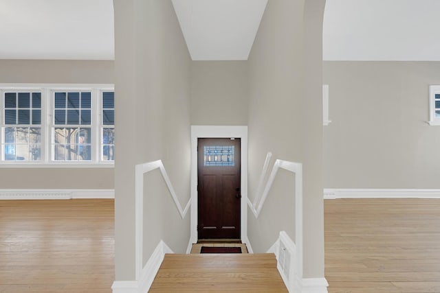 entryway featuring light wood finished floors, visible vents, baseboards, lofted ceiling, and a baseboard heating unit