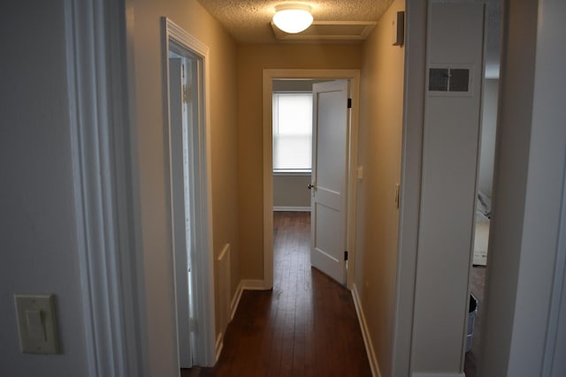 corridor with dark hardwood / wood-style flooring and a textured ceiling