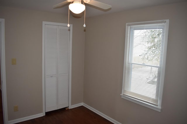 unfurnished bedroom with dark hardwood / wood-style flooring, ceiling fan, and a closet