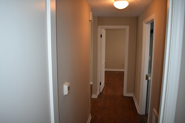 corridor with dark wood-type flooring and a textured ceiling