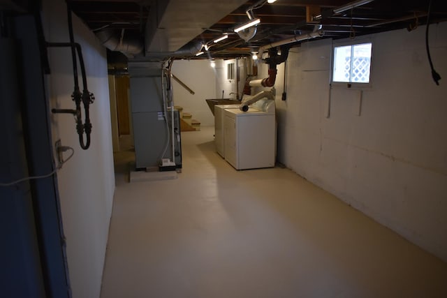 basement featuring washing machine and clothes dryer and heating unit