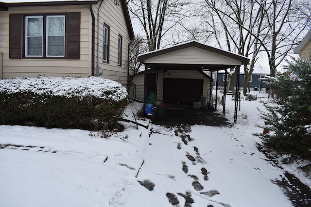 view of snowy exterior with a carport, an outdoor structure, and a garage