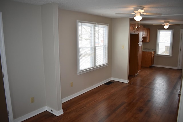 unfurnished dining area with a textured ceiling, dark hardwood / wood-style flooring, a wealth of natural light, and ceiling fan