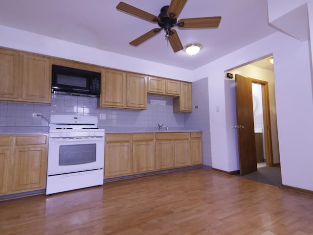 kitchen with tasteful backsplash, white range with gas cooktop, light wood-type flooring, ceiling fan, and sink