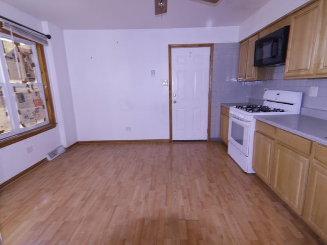 kitchen featuring white gas stove, light brown cabinetry, light hardwood / wood-style flooring, and decorative backsplash