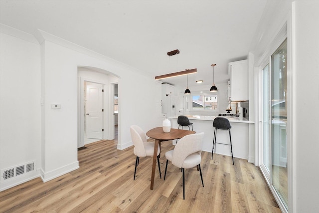 dining area with light hardwood / wood-style flooring and crown molding