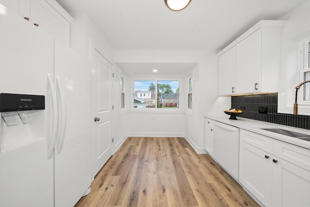 kitchen with tasteful backsplash, white cabinetry, light hardwood / wood-style floors, and white appliances