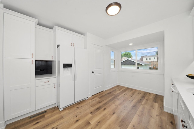 kitchen with light hardwood / wood-style floors, white cabinetry, and white refrigerator with ice dispenser