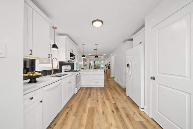 kitchen featuring kitchen peninsula, white appliances, sink, white cabinets, and hanging light fixtures