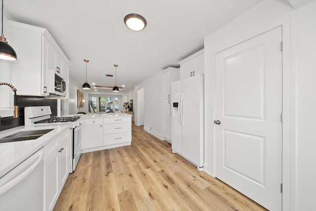 kitchen featuring kitchen peninsula, white appliances, decorative light fixtures, and white cabinetry