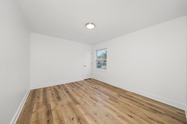 empty room with crown molding and light hardwood / wood-style floors