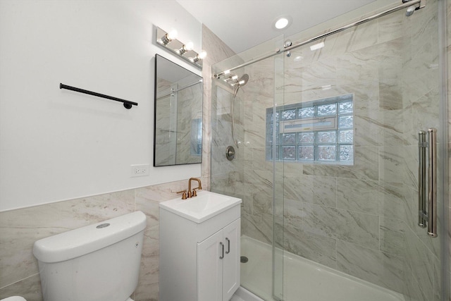 bathroom featuring vanity, toilet, a shower with door, and tile walls