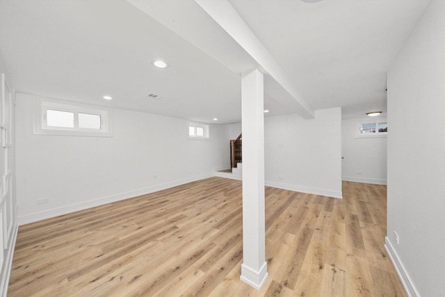 basement with a healthy amount of sunlight and light hardwood / wood-style floors