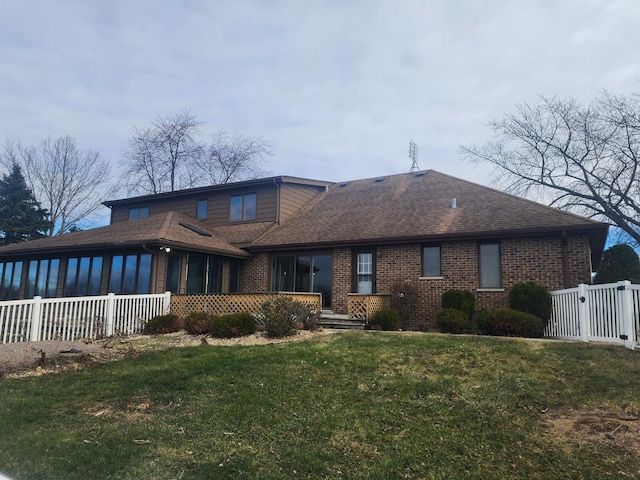 back of property with a lawn and a sunroom