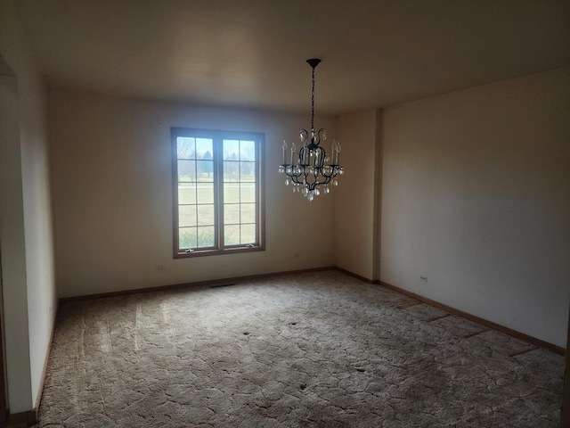 carpeted empty room featuring a chandelier