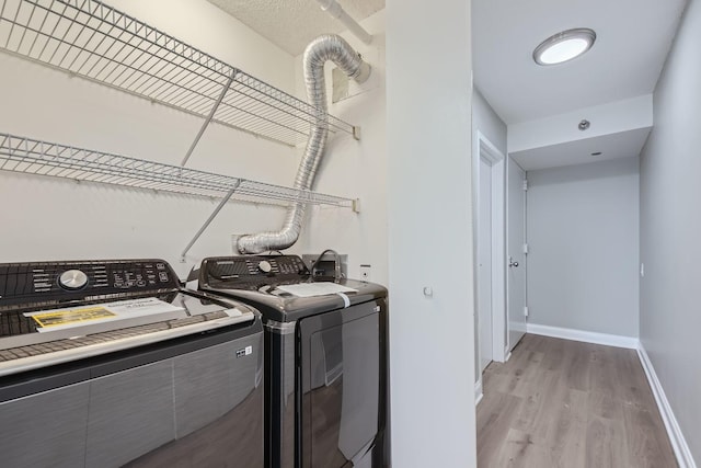 clothes washing area with light wood-type flooring and washer and clothes dryer