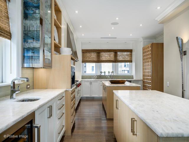 kitchen featuring white cabinetry, a center island, light stone counters, and sink