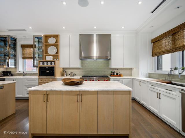 kitchen with white cabinets, a kitchen island, a wealth of natural light, and wall chimney range hood