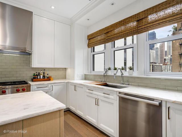 kitchen featuring sink, stainless steel appliances, wall chimney range hood, tasteful backsplash, and white cabinets