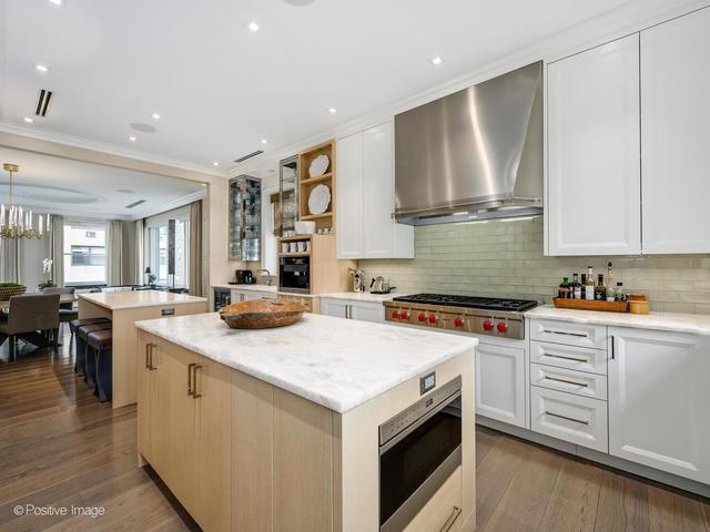 kitchen featuring pendant lighting, wall chimney range hood, a kitchen island, white cabinetry, and stainless steel gas cooktop