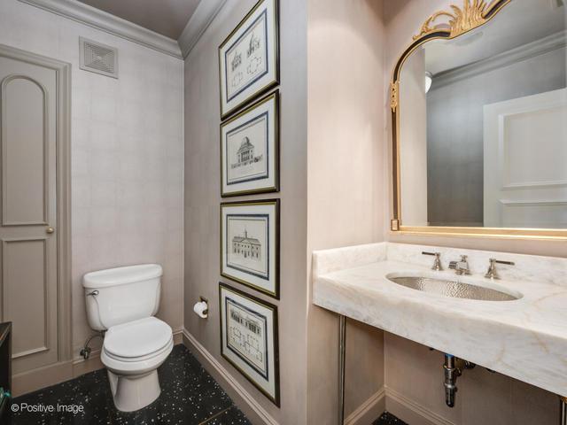 bathroom featuring toilet, ornamental molding, and sink