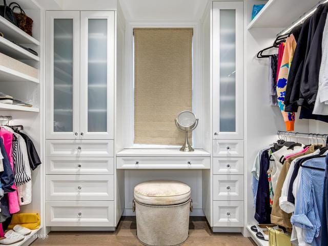 walk in closet with light hardwood / wood-style flooring