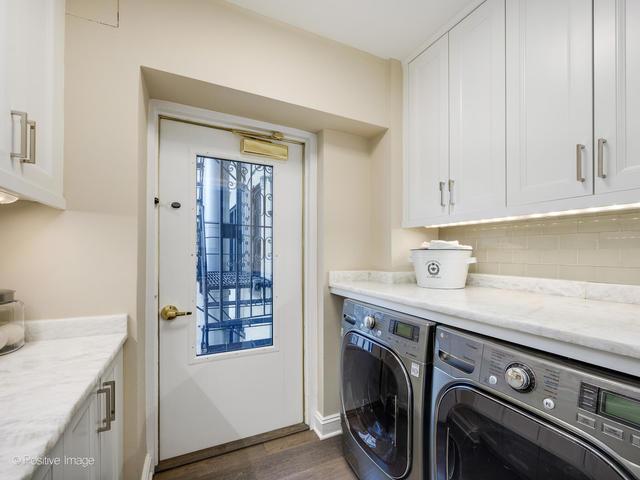 clothes washing area with washing machine and clothes dryer, dark wood-type flooring, and cabinets