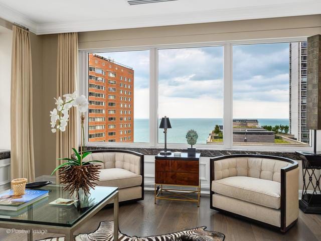 living area featuring hardwood / wood-style floors, a water view, and ornamental molding