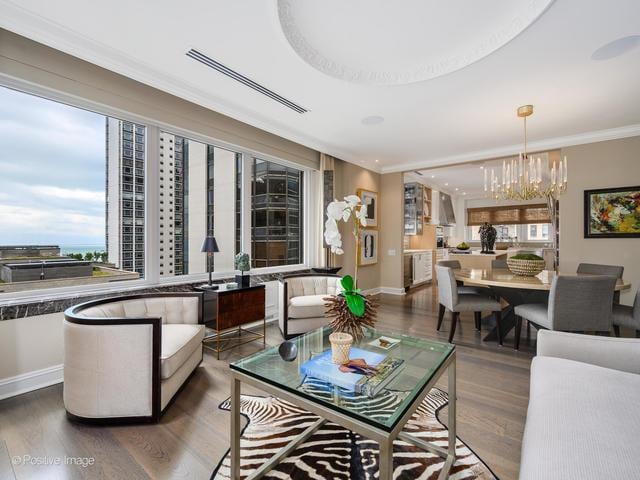 living room featuring a notable chandelier, ornamental molding, and dark wood-type flooring