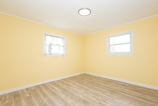 spare room with light hardwood / wood-style floors and crown molding