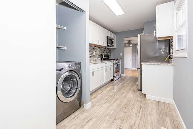 interior space featuring decorative backsplash, light wood-type flooring, white cabinetry, stainless steel appliances, and washer / clothes dryer