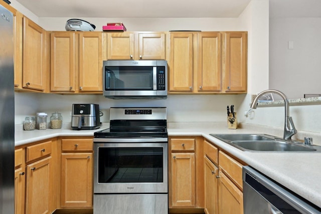 kitchen with appliances with stainless steel finishes, light brown cabinetry, and sink