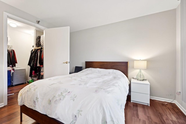 bedroom featuring a walk in closet, a closet, and dark wood-type flooring